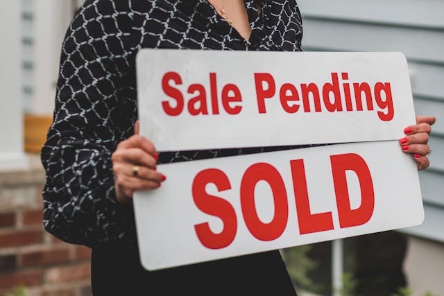 Real estate agent replacing sale pending with sold sign