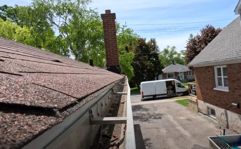 A brown shingle roof with a truck parked in front, set against a clear blue sky