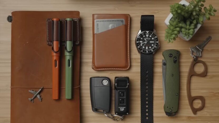 Everyday carry items are arranged neatly on a wooden desk