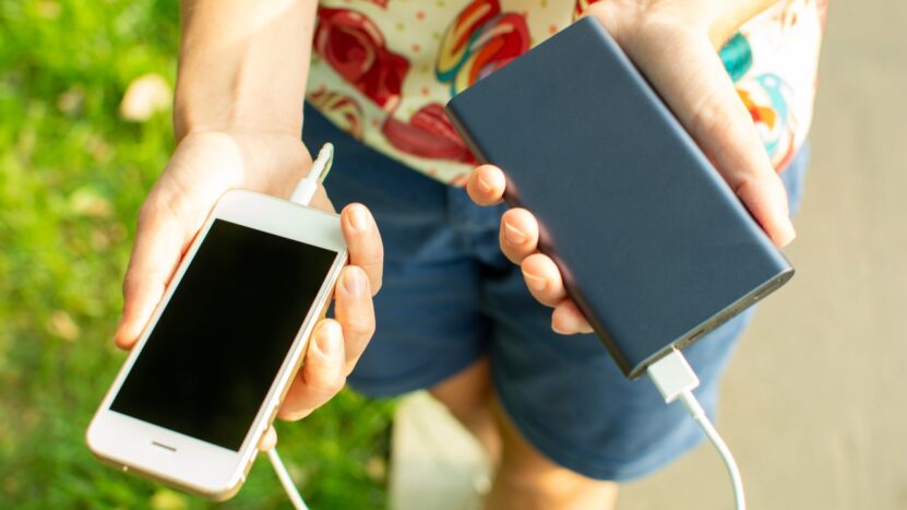 A person charges a phone with a power bank outdoors