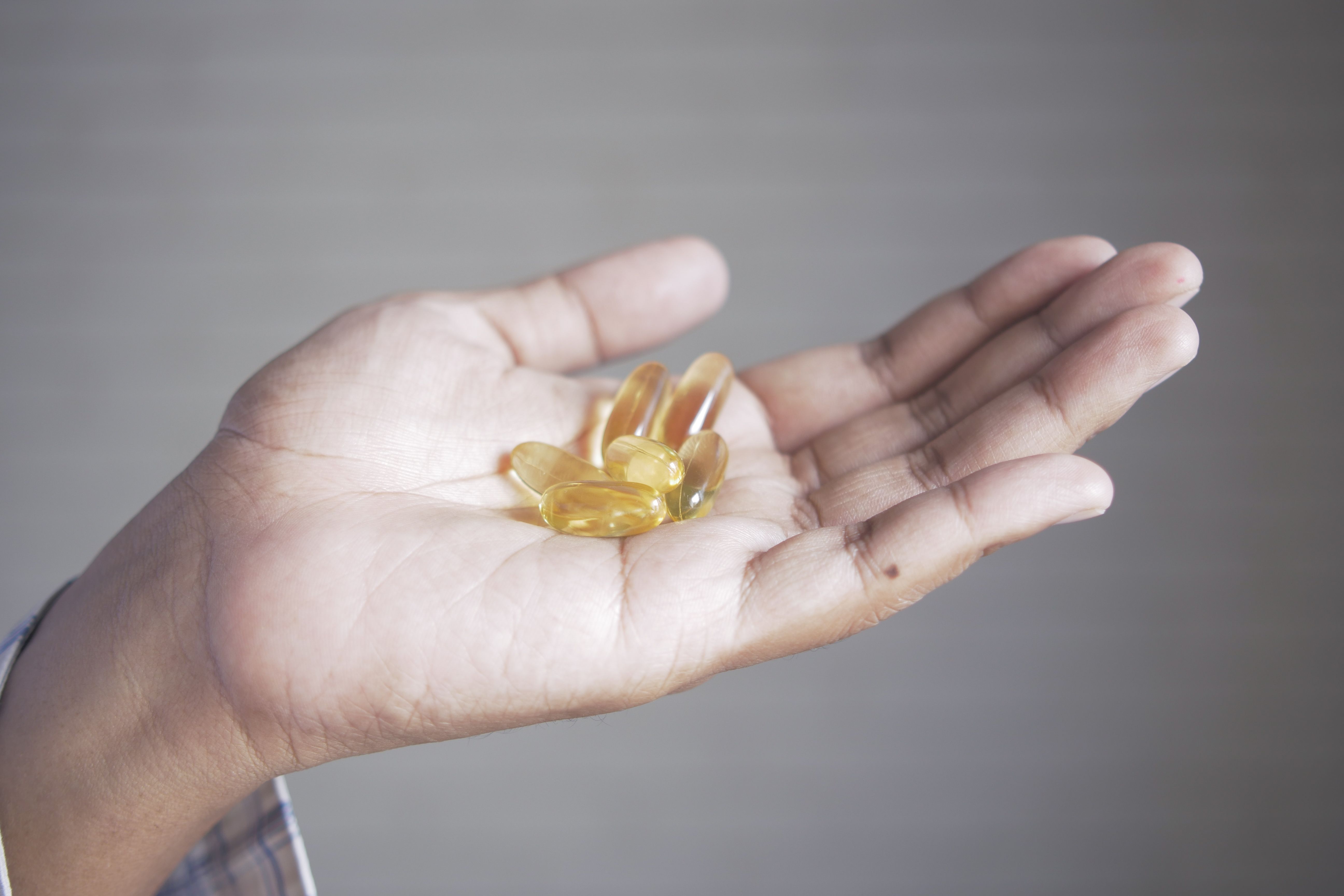A hand holding supplement capsules, illustrating the capsule form of collagen.