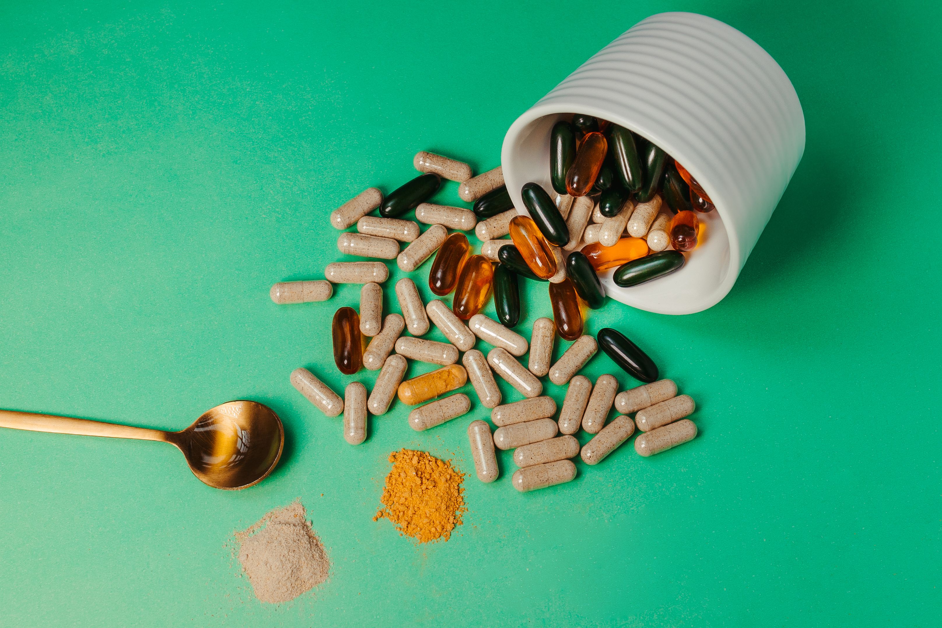 Capsules and powdered supplements arranged with a spoon for a direct form comparison.