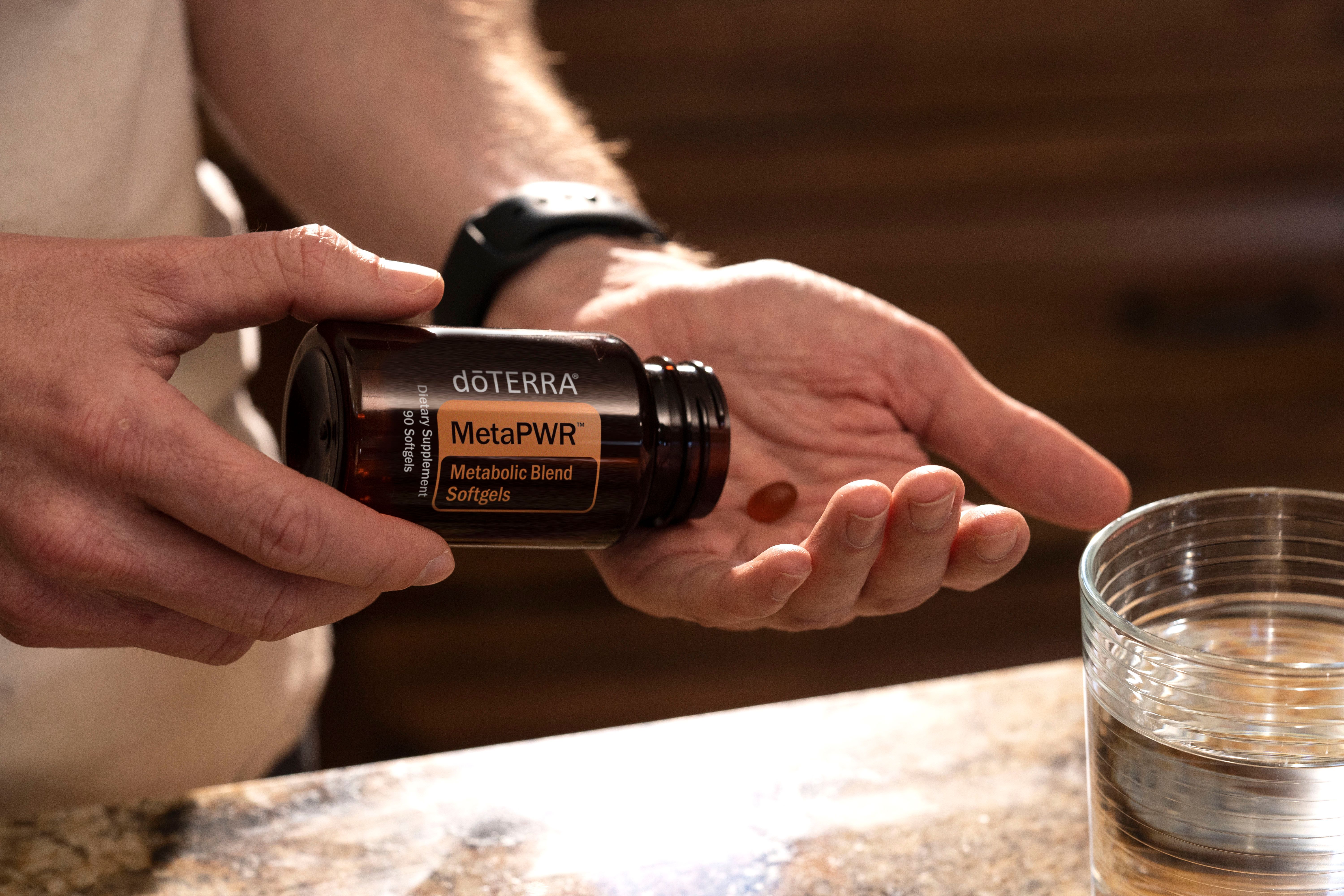 A hand holding supplements beside a glass of water, illustrating an easy daily wellness routine.