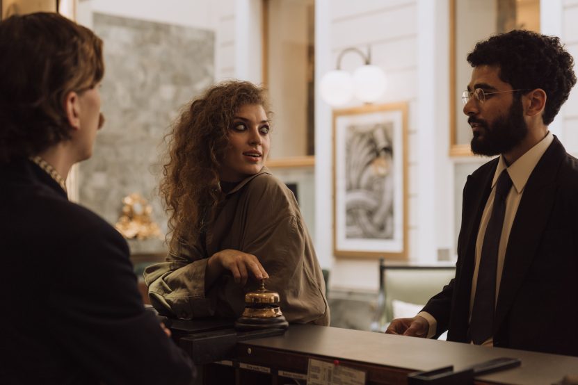 Hotel concierge assisting guests discreetly at a luxury reception desk.