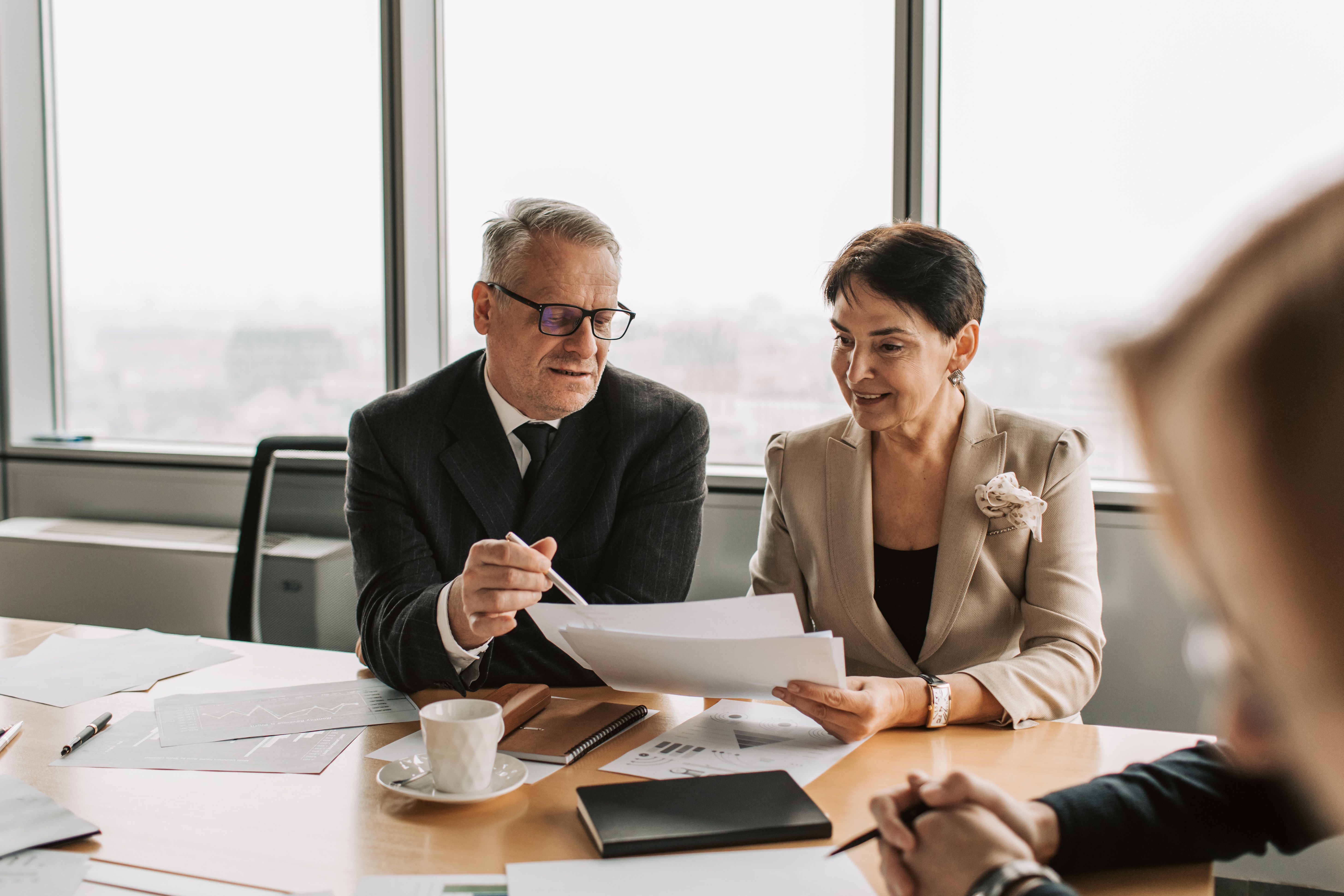 Senior business professionals reviewing documents in a private corporate meeting.
